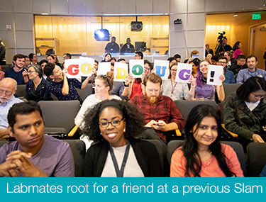 audience holds up sign at previous postdoc slam event