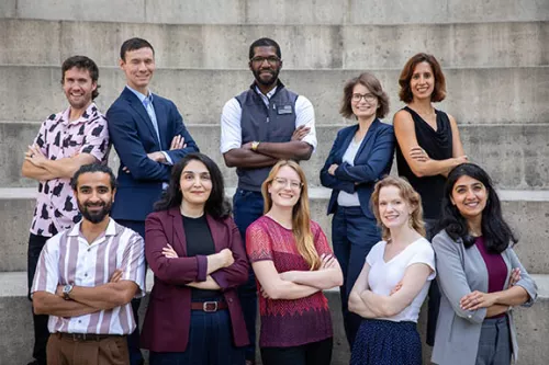 Ten Postdoc Slam finalists pose for a group photo on the steps outside Genentech Hall at UCSF