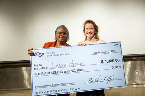 Nicquet Blake and Postdoc Slam first prize winner Laura Persson hold the giant check indicating a prize of $4,000