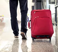 Person wheeling red luggage